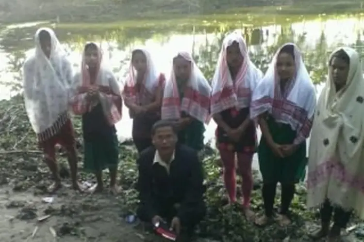 people lined up by a river for baptism, with pastor