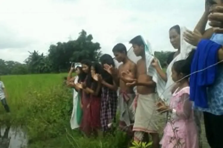 group of people praying by the river before being baptised